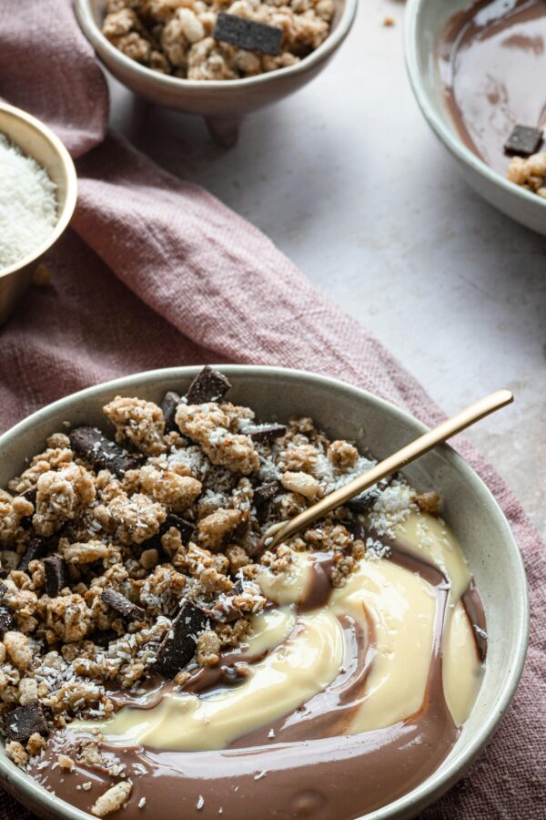 Close-up of a granola and chocolate dessert bowl with creamy texture for a delightful treat.